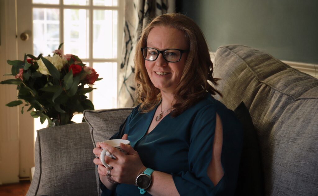 Woman sitting on a sofa holding a mug, relaxed natural light portrait for personal brand photography