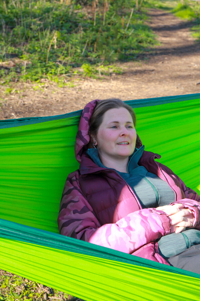 Woman relaxing in a green hammock outdoors in natural light