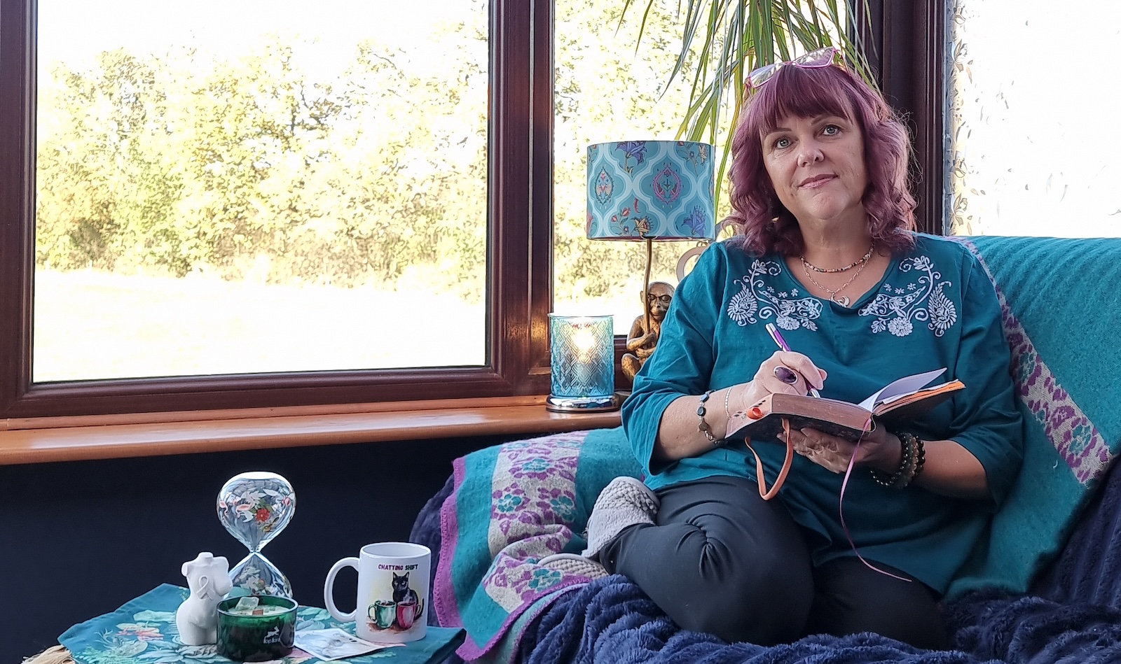 Woman sitting comfortably at home with a notebook, relaxed and natural in her own space
