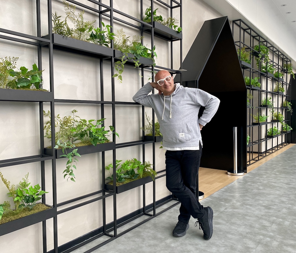 Man relaxing naturally during a virtual brand photoshoot beside indoor planting shelves