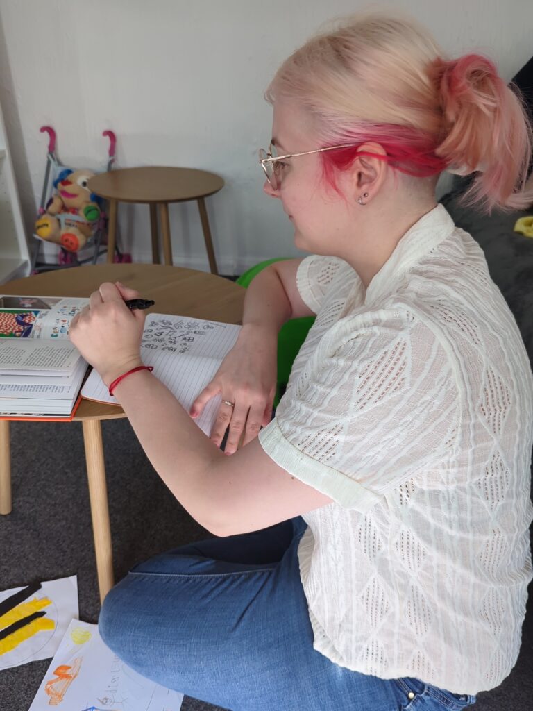 Business owner writing in a notebook during a guided virtual brand photo shoot at home.