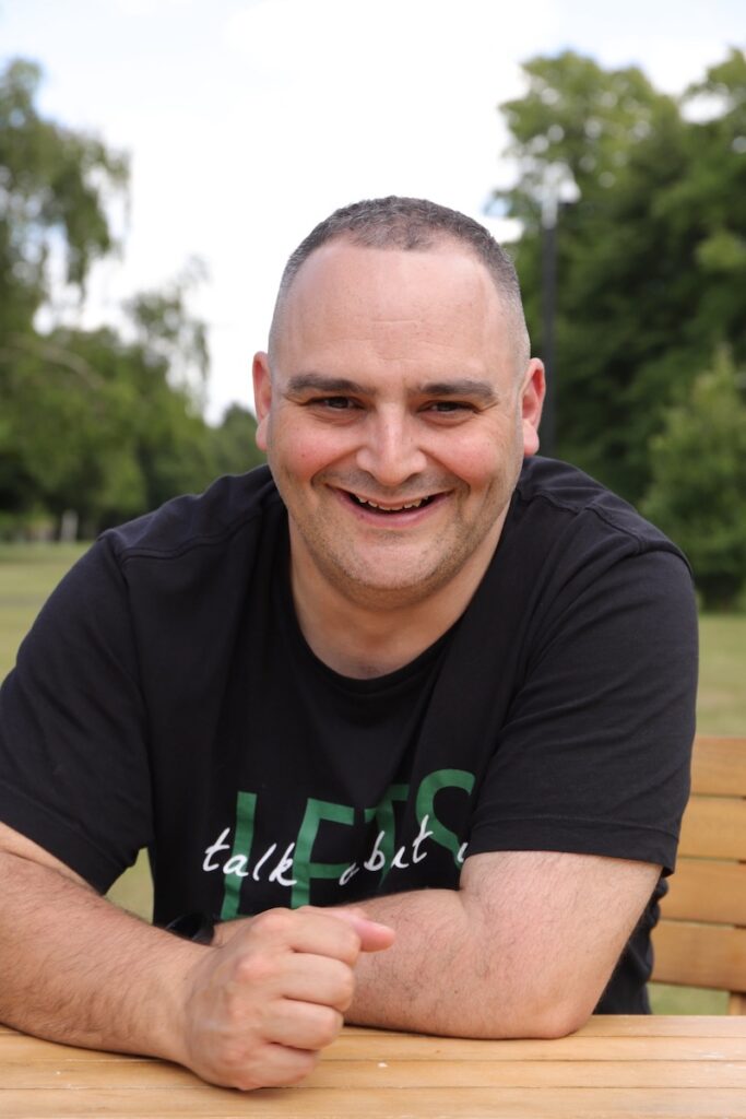 Smiling male business owner sitting outdoors during a relaxed brand photo shoot in a park